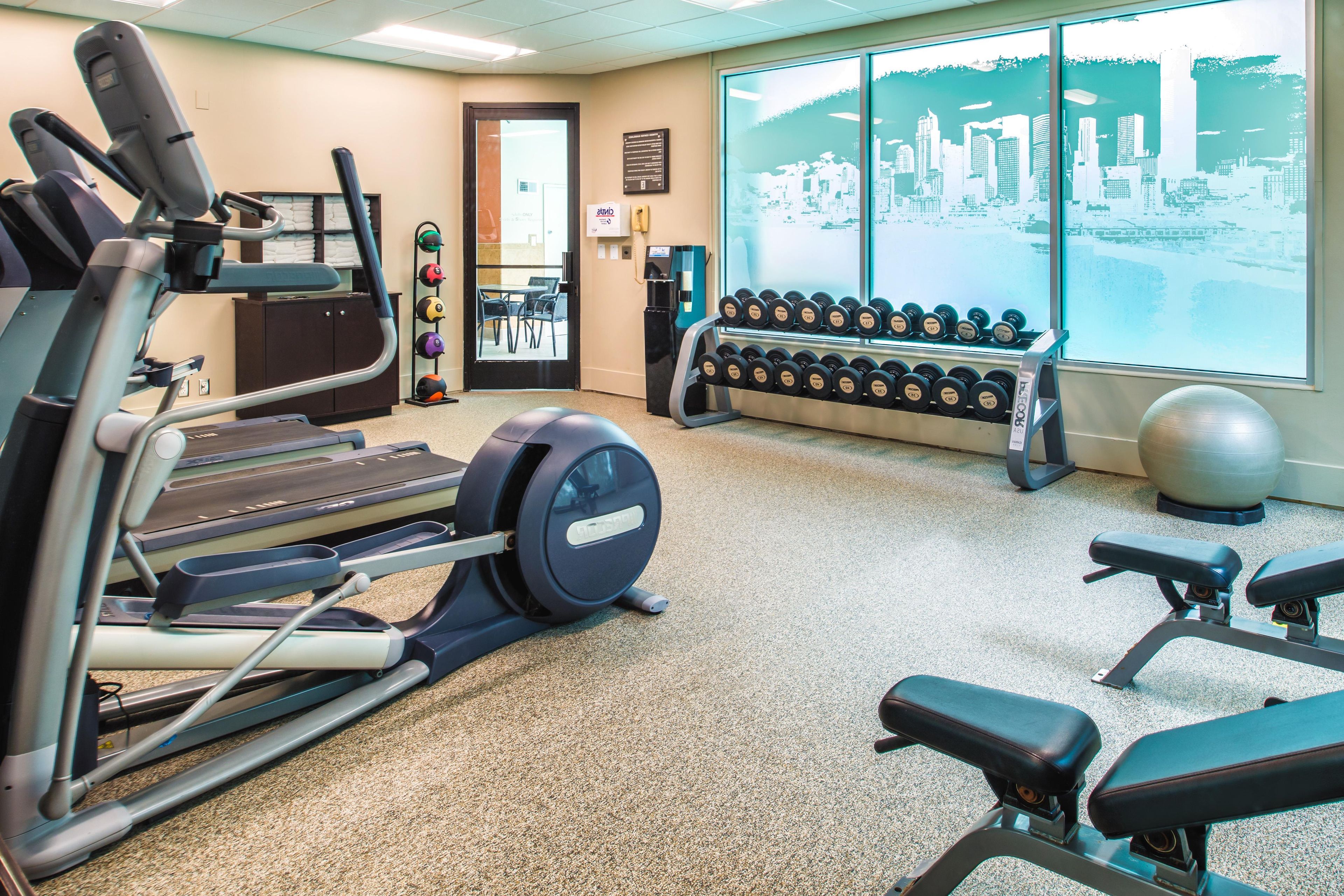 Un gimnasio con equipo de cardio, mancuernas y pelotas de ejercicio.