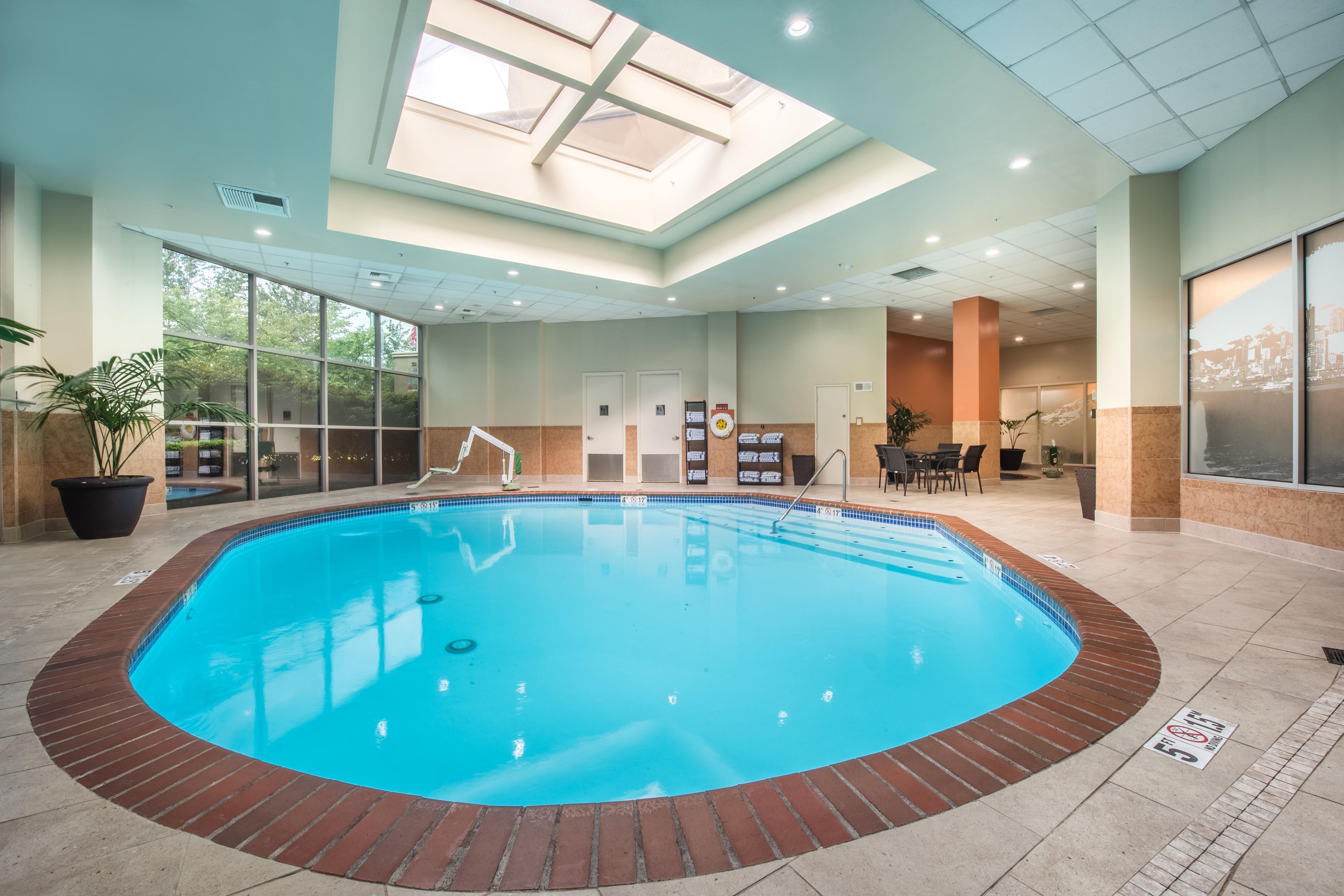 Una piscina interior con tragaluces, un vestuario y una zona de estar con vistas a la ciudad.