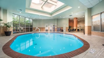 Una piscina interior con tragaluces, un vestuario y una zona de estar con vistas a la ciudad.