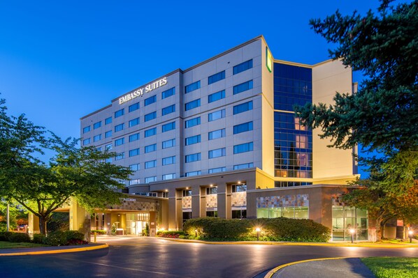 A multi-story hotel with a modern design, featuring a prominent "Embassy Suites" sign, a well-lit entrance, and a landscaped driveway. - Embassy Suites by Hilton Seattle Tacoma International Airport (Tukwila)