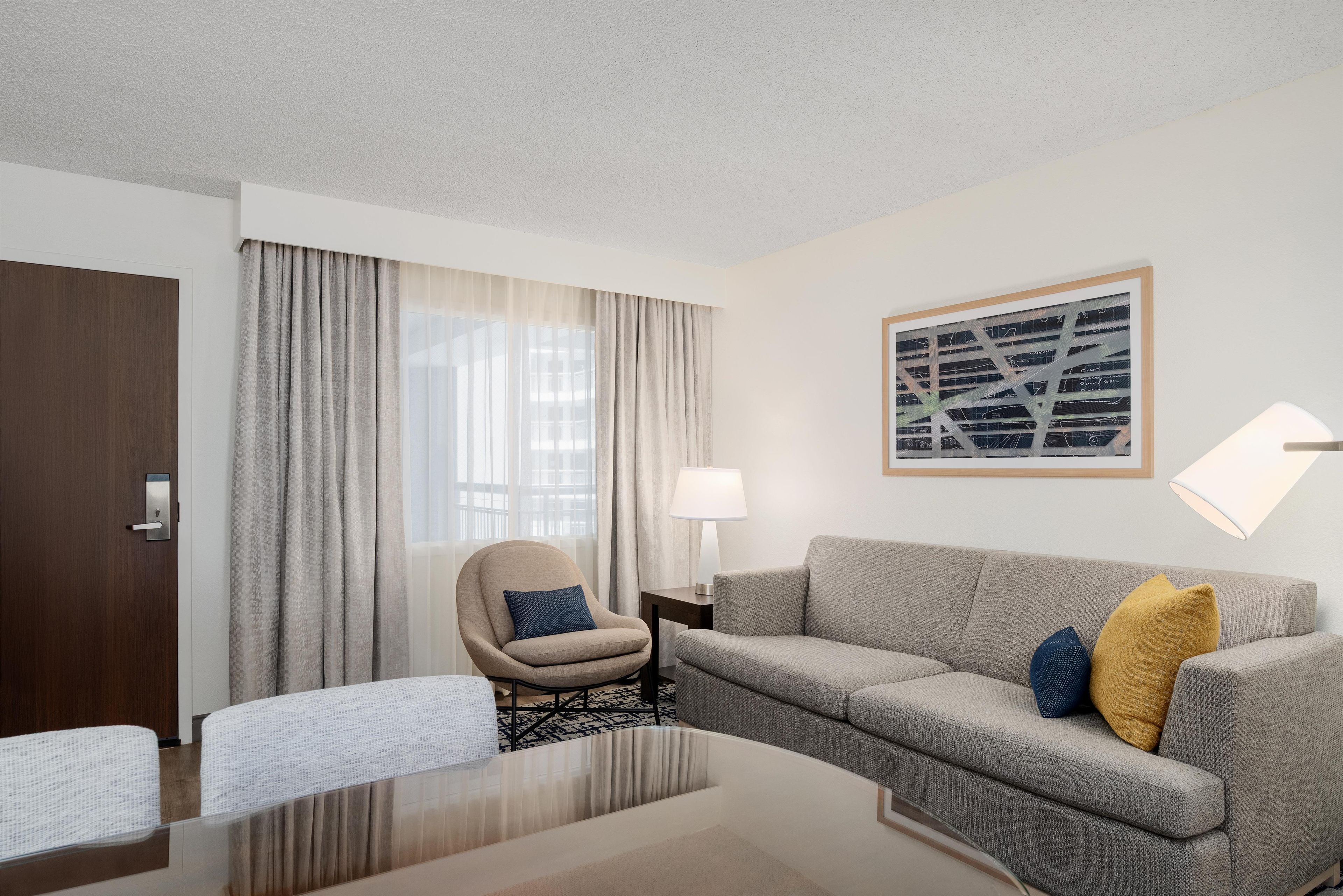 Une chambre d’hôtel avec un canapé, un fauteuil et une table.