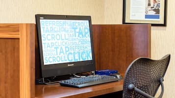 A computer desk with a monitor displaying a word cloud, a keyboard, and a mouse.