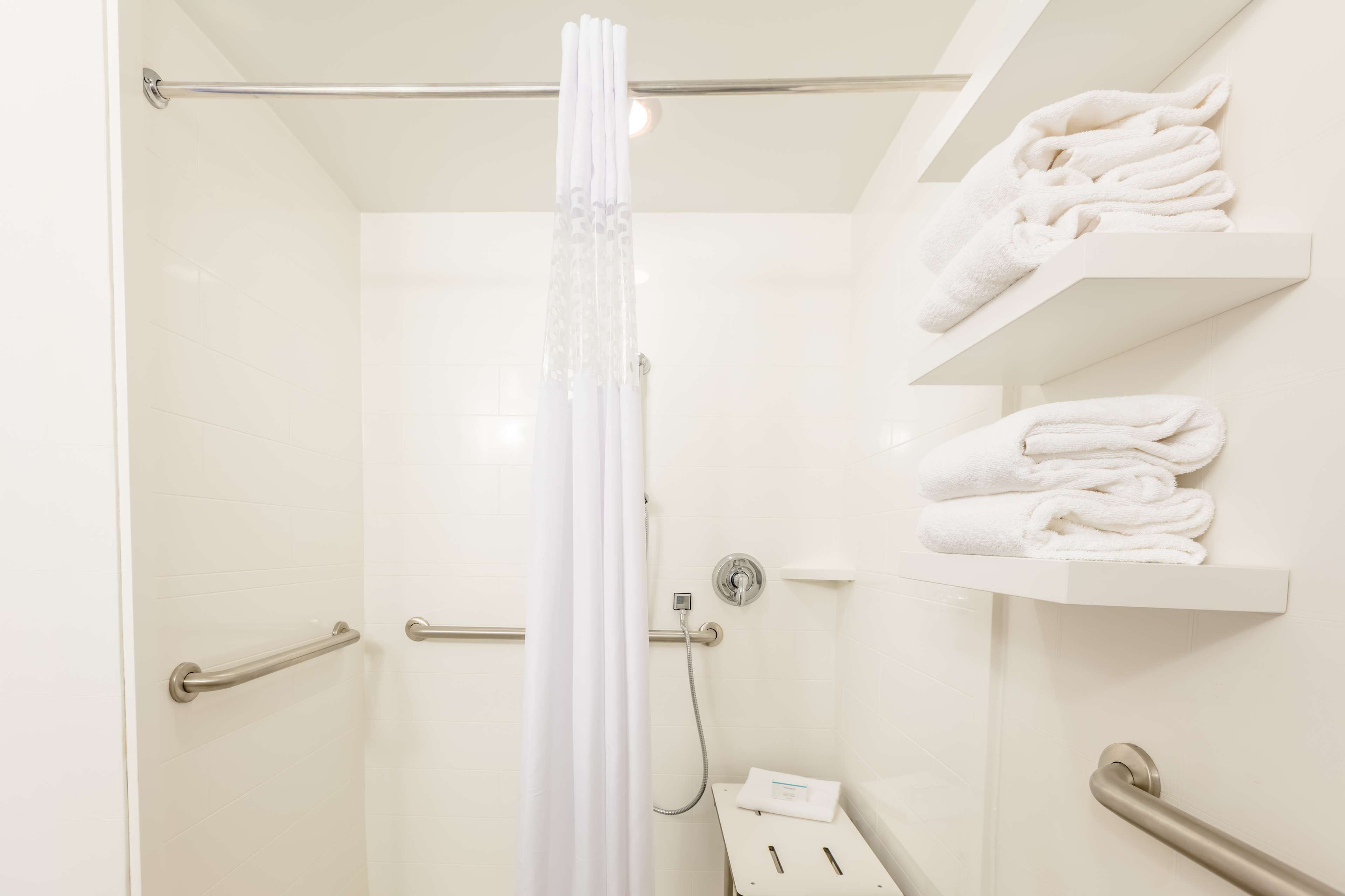 A bathroom with a shower, a towel rack, and a hand dryer.
