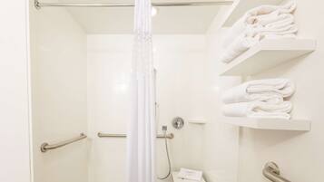 A bathroom with a shower, a towel rack, and a hand dryer.