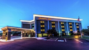 A Hampton Inn hotel with a modern facade, large windows, and an American flag.