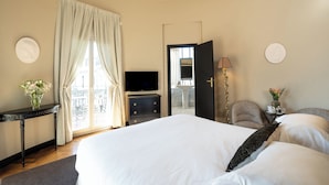 Habitación de hotel con cama, televisión, escritorio, silla y vista al exterior.