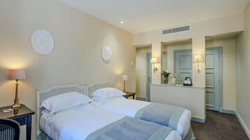 A hotel room with two beds, a nightstand, a lamp, a mirror, and a wardrobe.