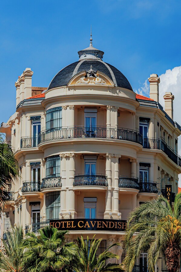 Un hotel de varios pisos con una cúpula, balcones y un letrero que dice 'HOTEL CAVENDISH'.