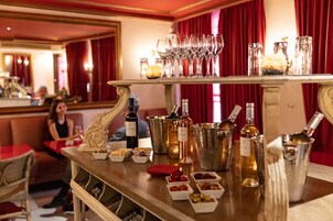 Een bar met een selectie wijnen en cocktails, glazen en kleine schaaltjes met snacks.