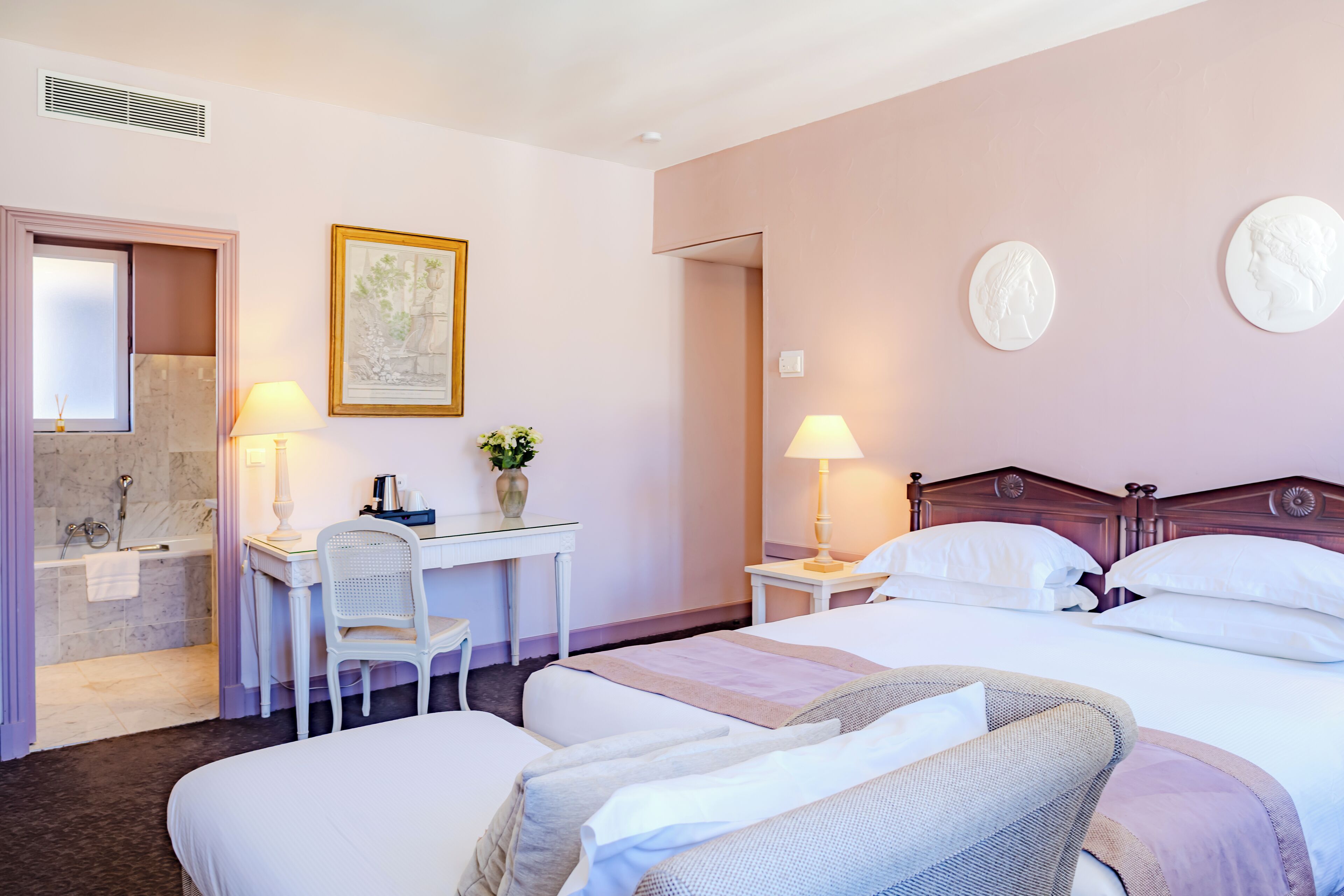 A hotel room with a bed, desk, chair, and a bathroom with a bathtub and shower.
