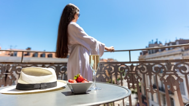 A balcony with a table, a hat, a glass of champagne, and strawberries. - Cavendish (Cannes)