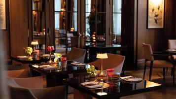 A well-lit dining area with tables set for two, featuring modern decor and ambient lighting.