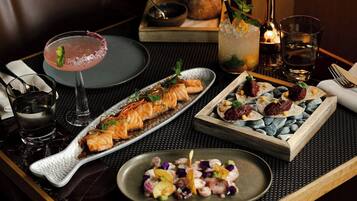 A dining table with a variety of dishes, a cocktail, and a candle.
