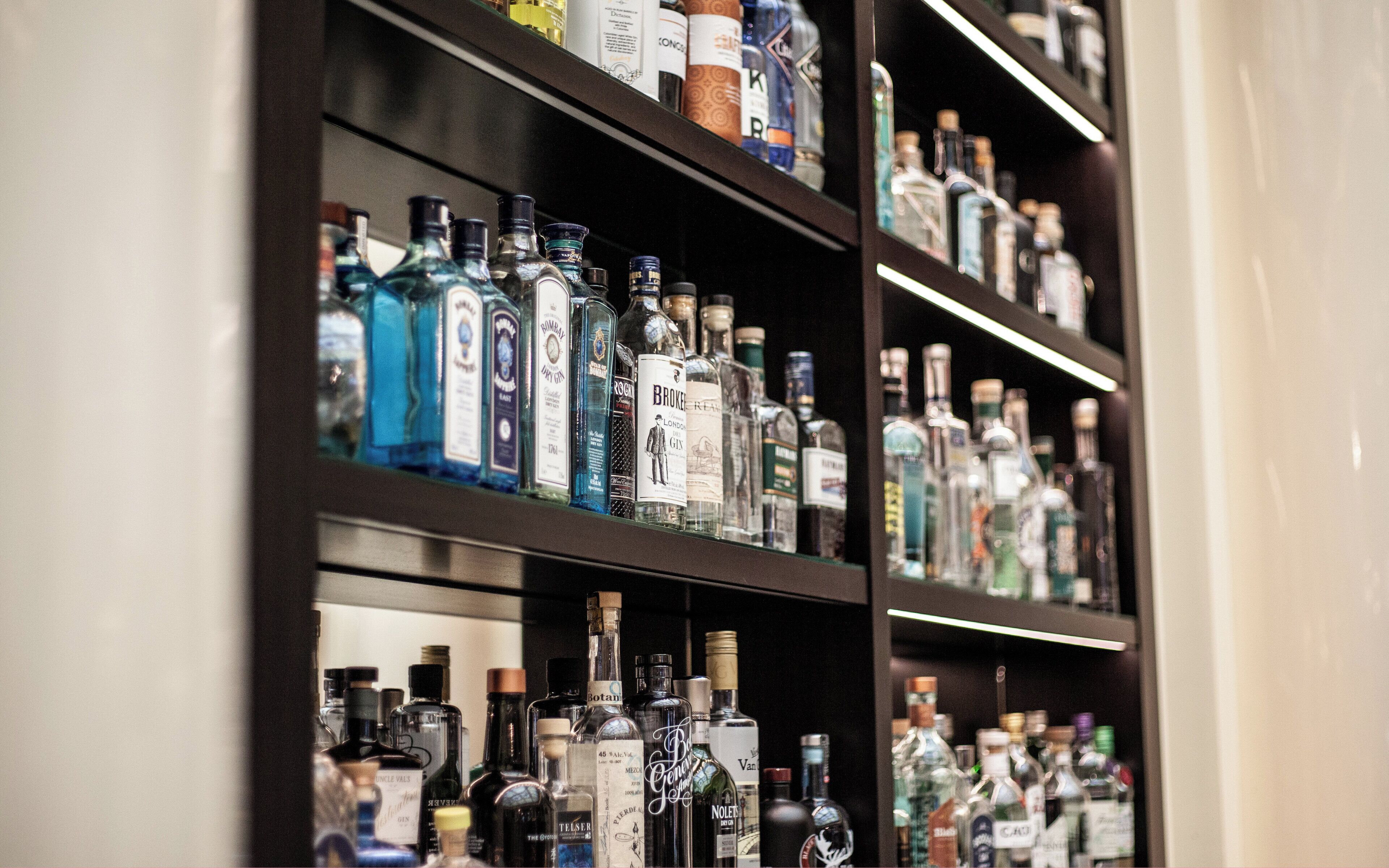 A variety of liquor bottles on shelves in a bar setting.