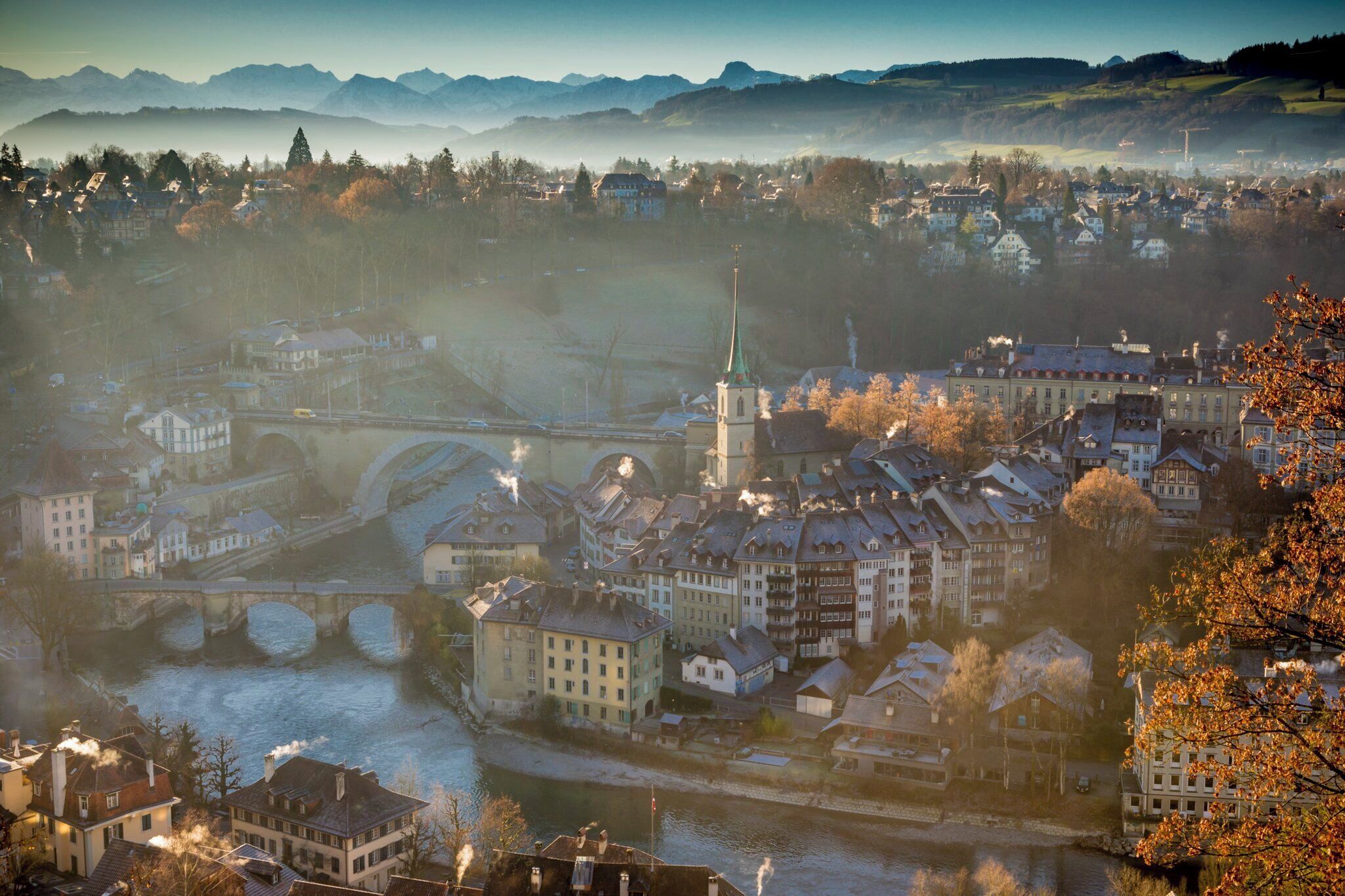 A riverside town with historic buildings, a prominent church, and a bridge.