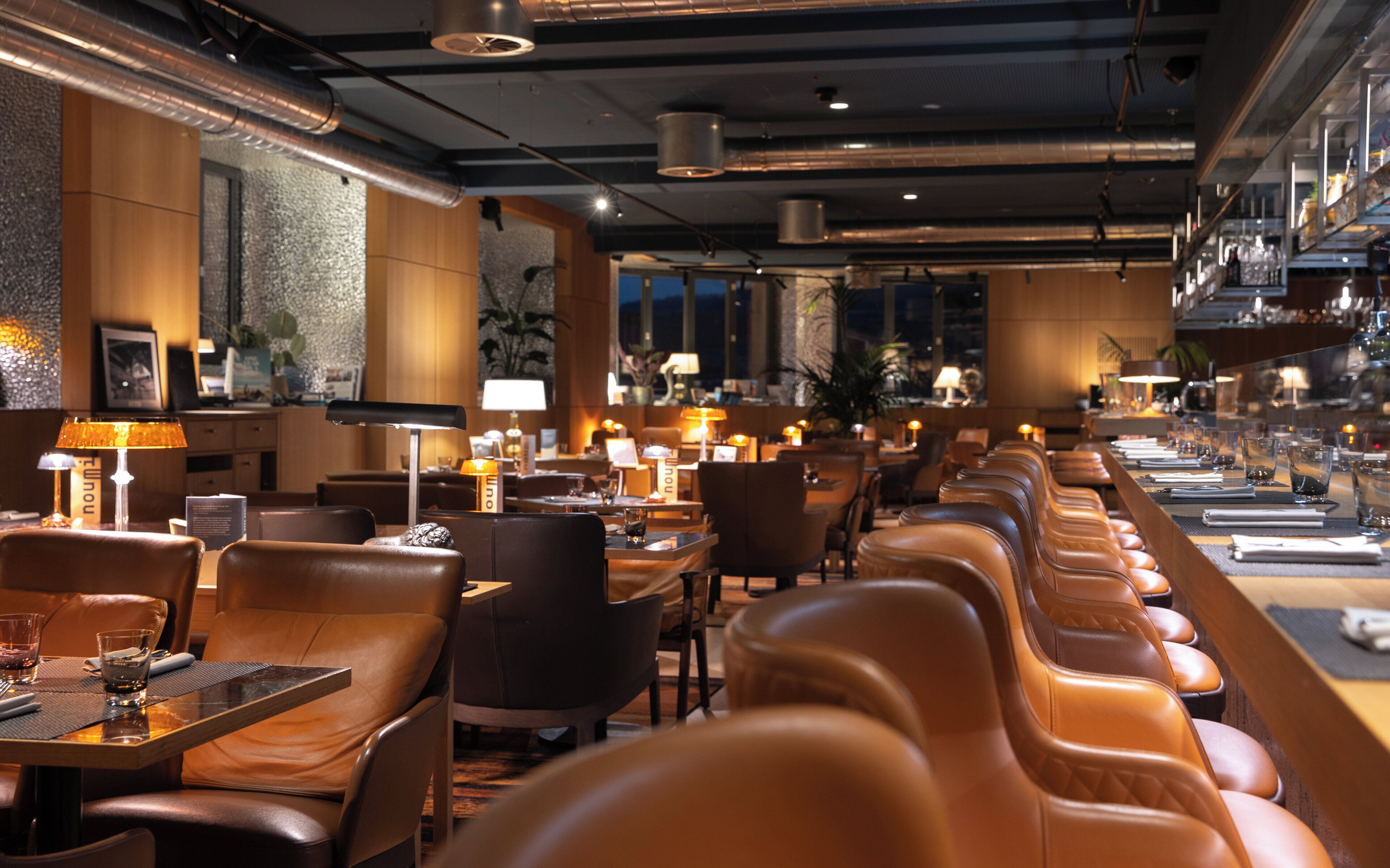Ein Restaurant mit Ledersitzbänken, Tischen und stimmungsvoller Beleuchtung.