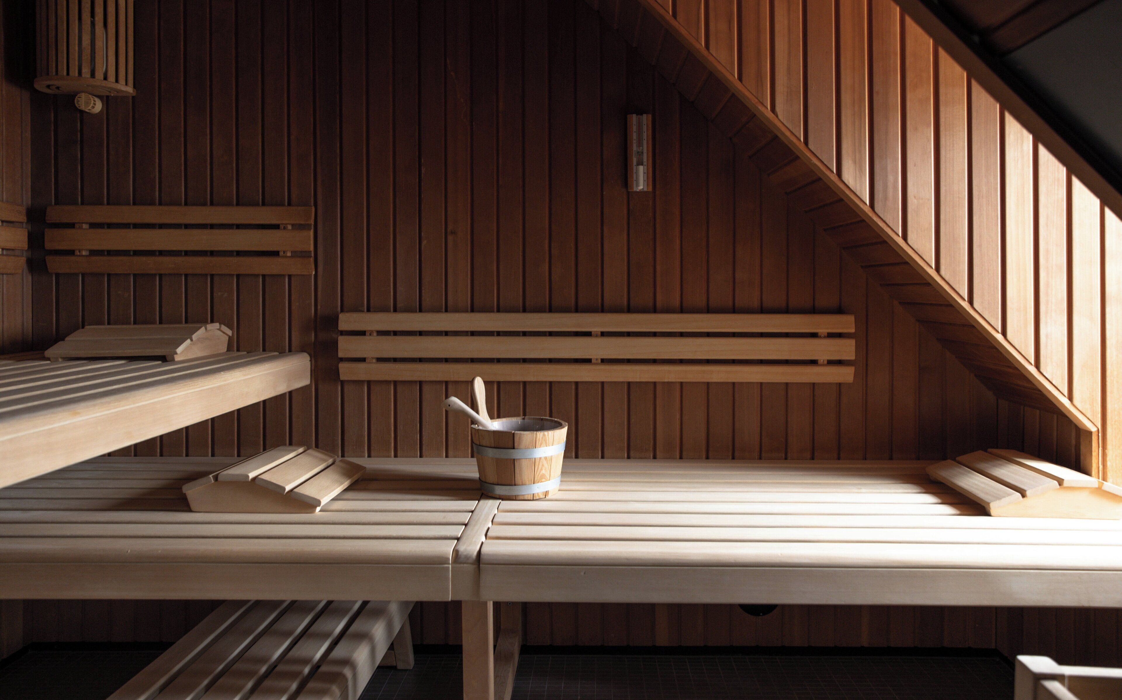 Un sauna avec des bancs en bois et un seau.