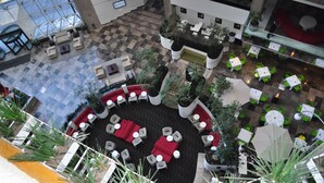 A high-ceiling atrium with a checkered floor, seating areas with red and white furniture, and green chairs. - Radisson Paraiso Hotel Mexico City (Mexico City)