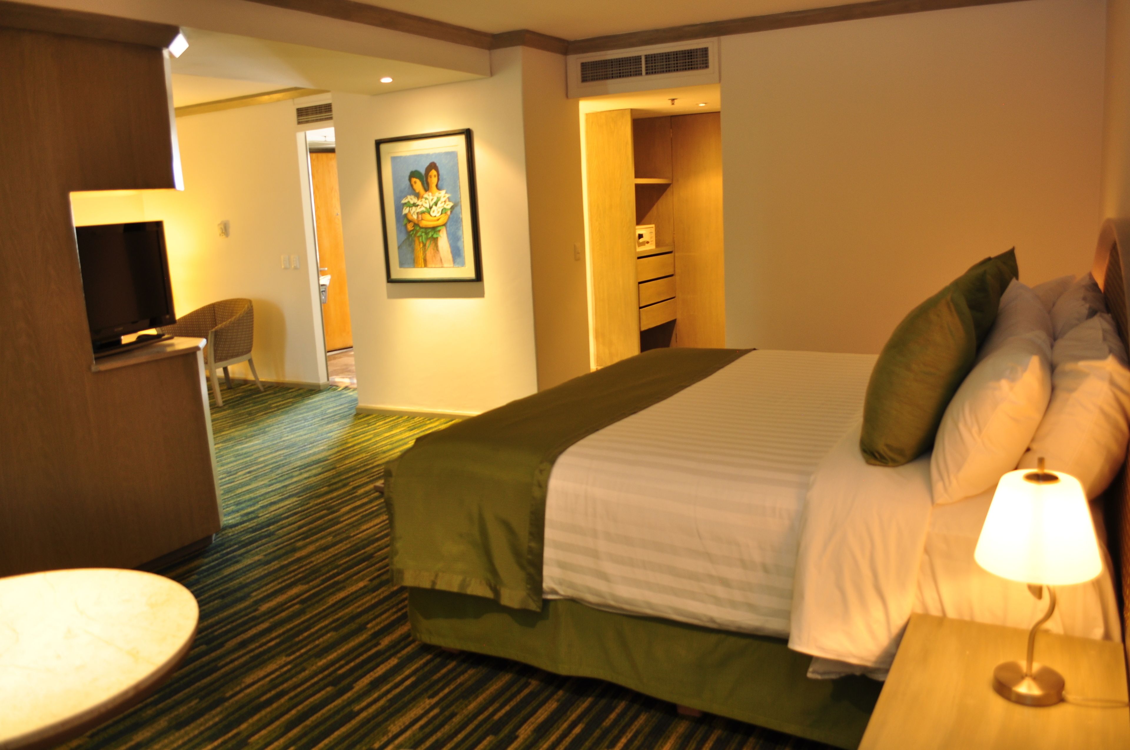 Una habitación de hotel con cama, televisión, escritorio y silla.