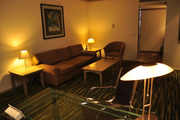 A hotel room with a sofa, a chair, a small table, and a glass partition. - Radisson Paraiso Hotel Mexico City (Mexico City)