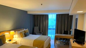 A hotel room with two beds, a desk with a TV, and a view of the outdoors through large windows. - Radisson Paraiso Hotel Mexico City (Mexico City)
