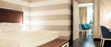 A hotel room with a large bed, a bench, a desk, and a chair.