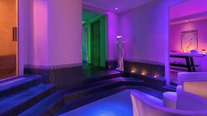 A spa area with a mosaic-tiled floor, a statue, and a seating area with a table and chairs. - Sina De la Ville (Milan)