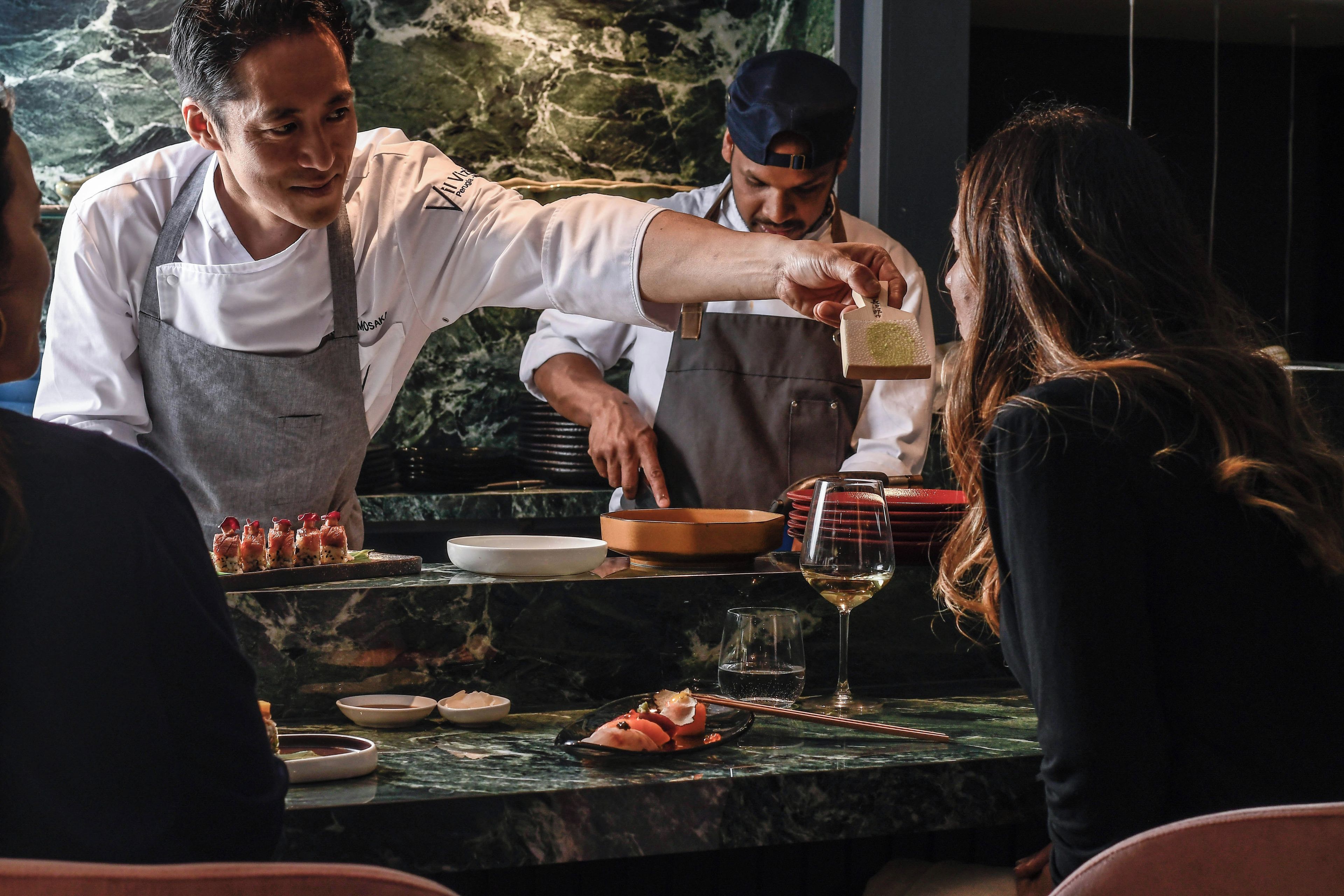 A restaurant setting with a marble countertop, a wine glass, and a dish of food.