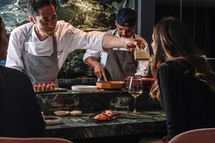 A restaurant setting with a marble countertop, a wine glass, and a dish of food.