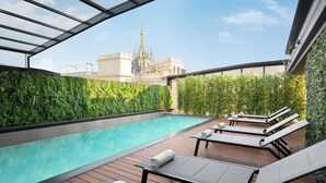 A rooftop pool with lounge chairs, a view of a cathedral, and a green wall. - Sina De la Ville (Milan)