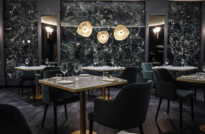 A restaurant with marble walls, round tables, and modern chairs. - Sina De la Ville (Milan)