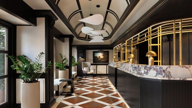 A reception area with a marble counter, potted plants, and a patterned floor. - Sina De la Ville (Milan)