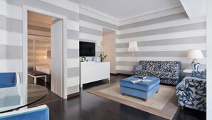 Un salon moderne avec un canapé, un pouf et une table en verre.