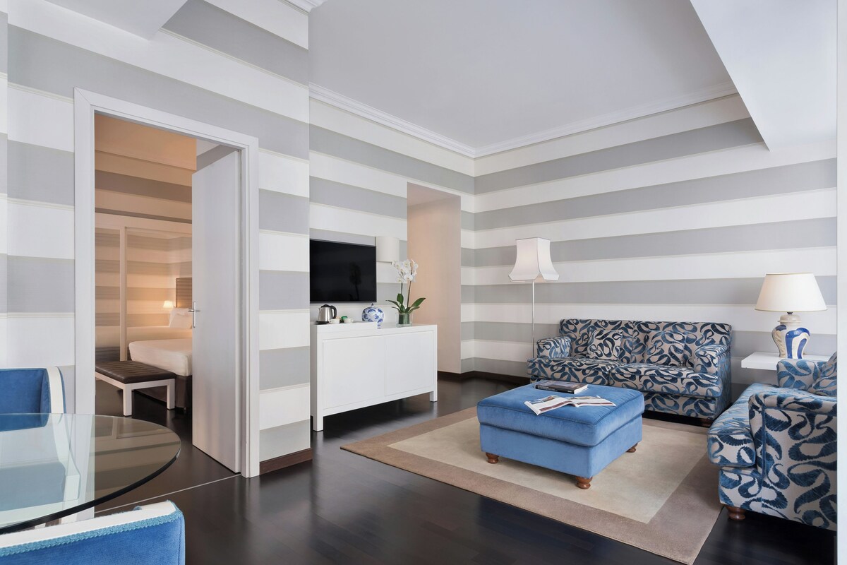 A modern living room with a sofa, ottoman, and a glass table.