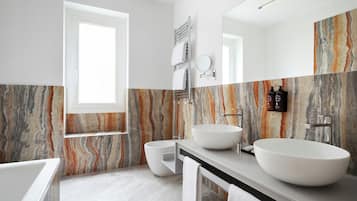 Un baño moderno con dos lavamanos grandes, un inodoro y una bañera.