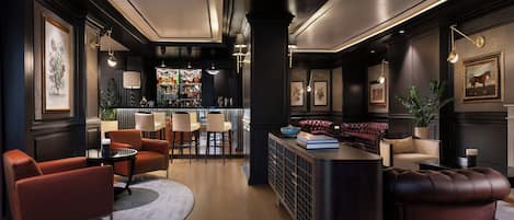 A bar area with a counter, seating, and a bar stocked with bottles.
