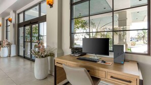 A modern office space with a wooden desk, computer, and potted plants.