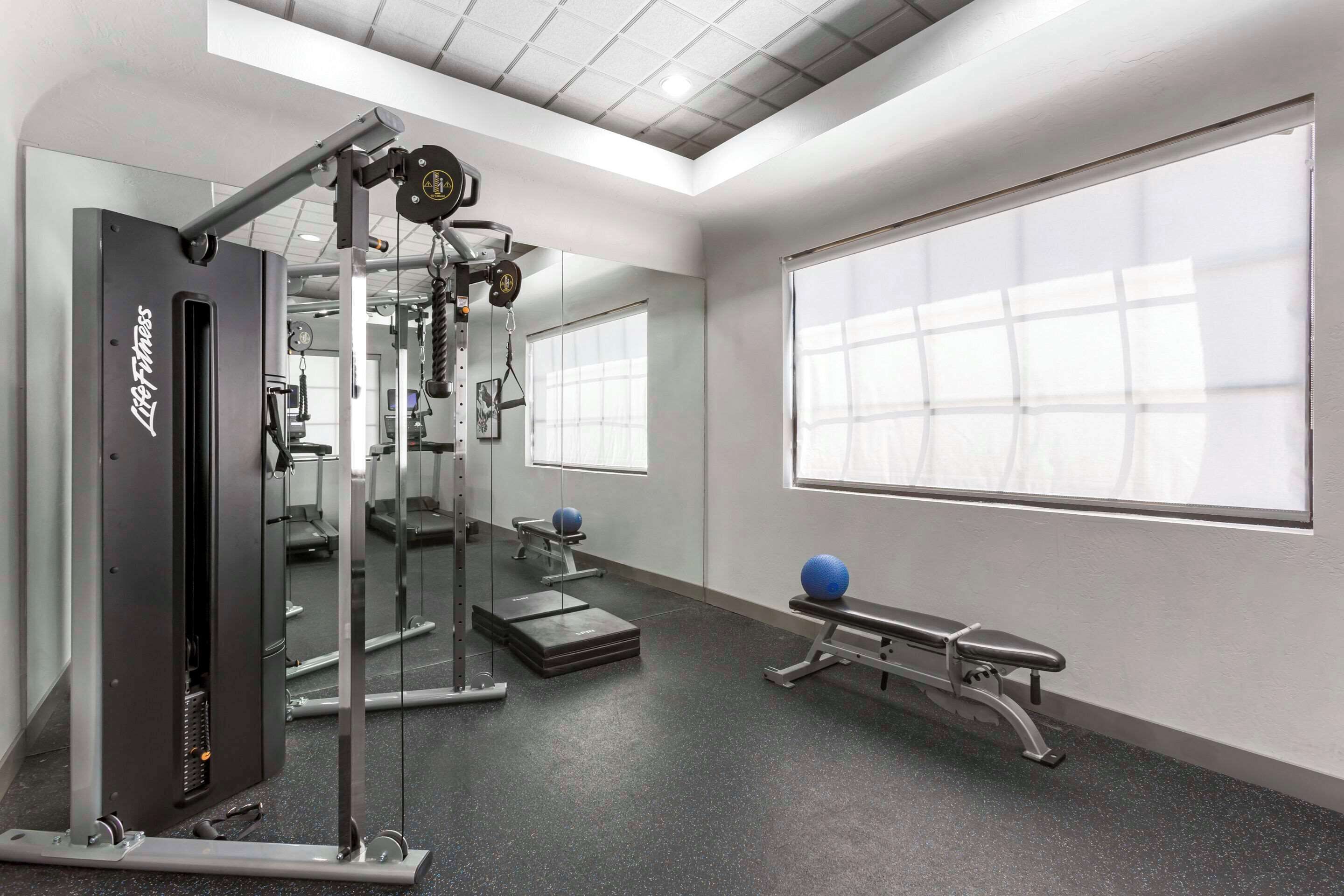 Un gimnasio con equipo de levantamiento de pesas, una banca y pelotas de ejercicio.