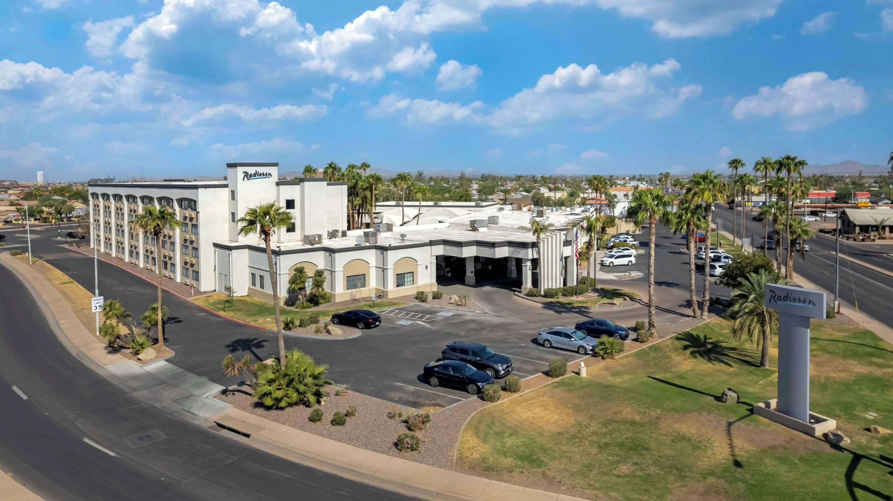 A Radisson hotel with a parking lot, palm trees, and a clear sky.