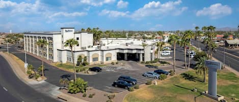 A Radisson hotel with a parking lot, palm trees, and a clear sky.
