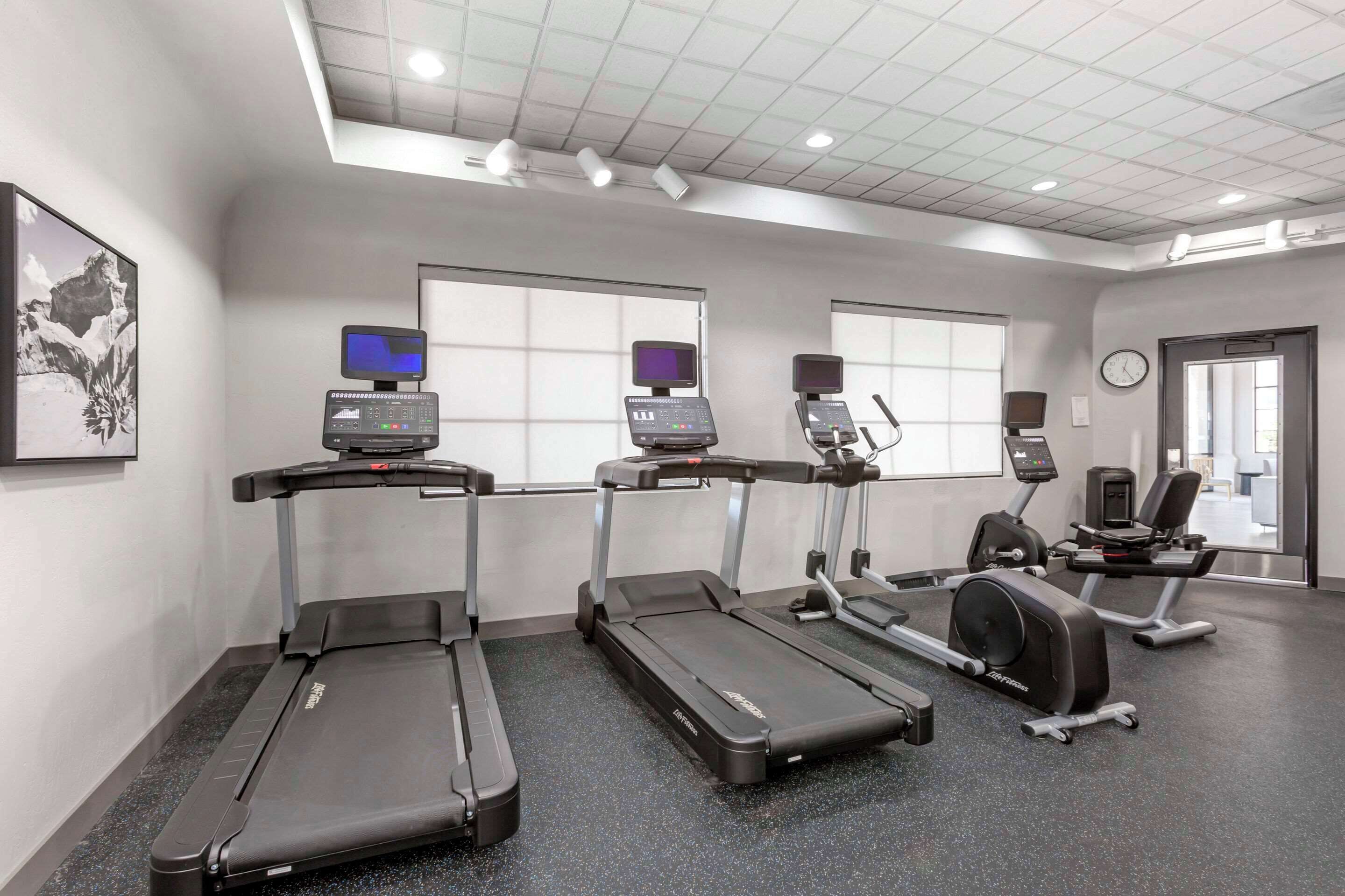 A gym with treadmills, a stationary bike, and a rowing machine.