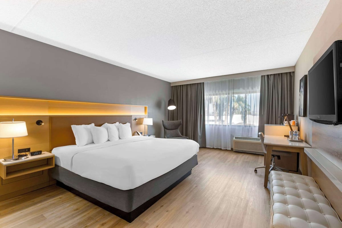 Una habitación de hotel moderna con una cama grande, mesitas de noche, un escritorio y un televisor.