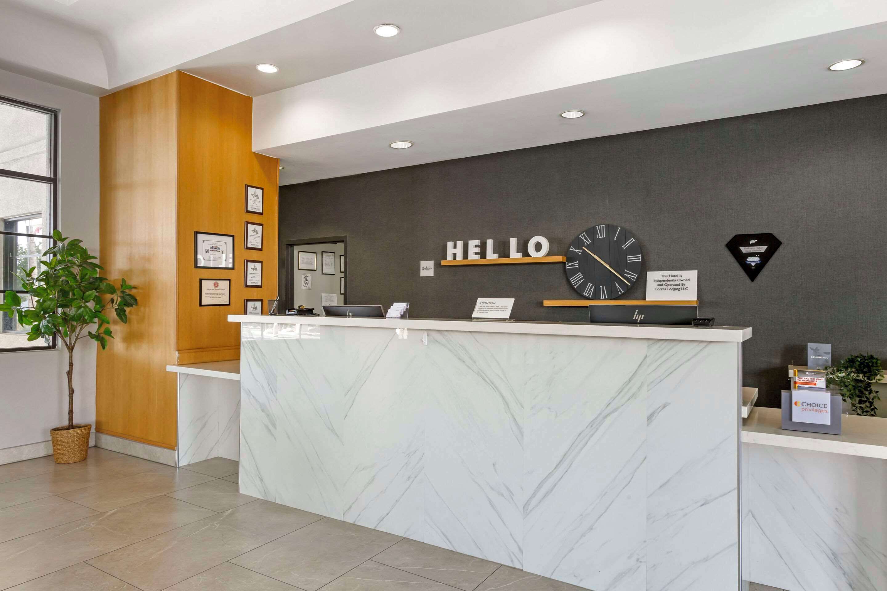 En hotelreception med en marmor disk, indrammede attester på væggen og et ur.