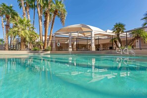 A swimming pool with a clear blue water surface, surrounded by a white fence and palm trees. - Radisson Hotel Casa Grande (Casa Grande)
