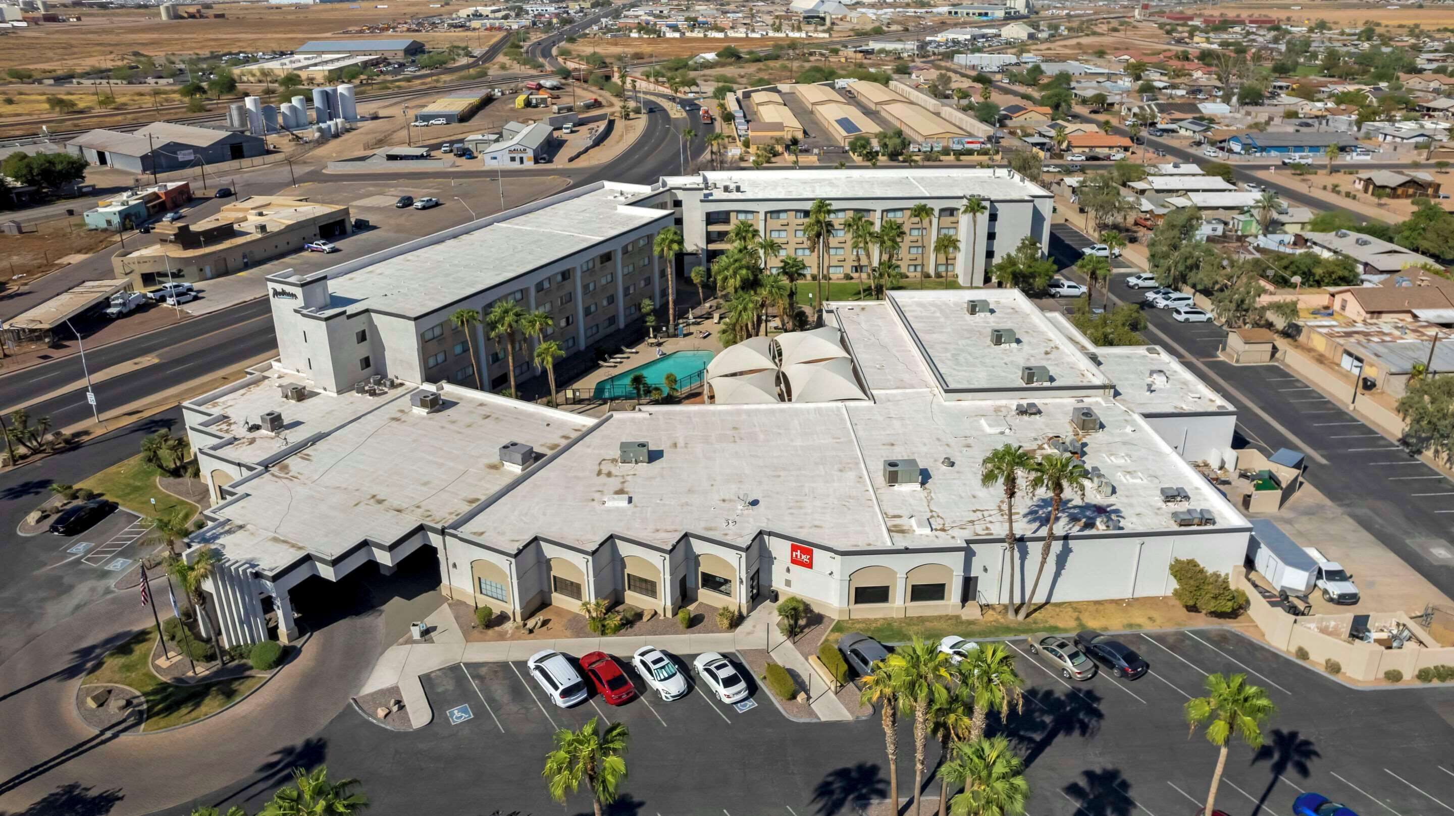 Un immeuble à plusieurs étages doté d’un toit plat, d’un parking et d’une piscine.