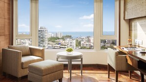 A modern room with a large window, a round table, two armchairs, and a desk with a lamp. - President, Mumbai - IHCL SeleQtions (Mumbai)