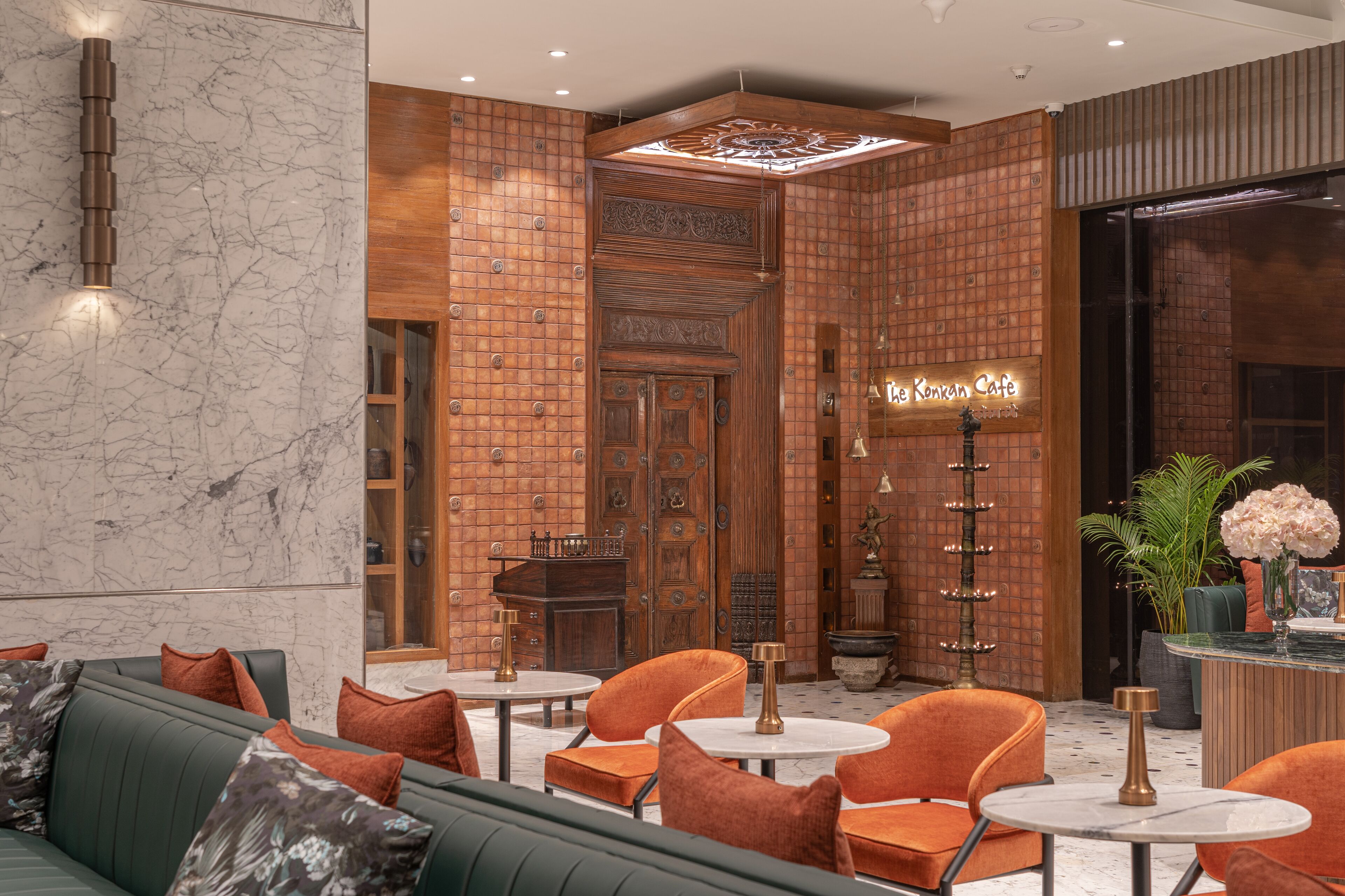 A modern interior with a green sofa, orange chairs, and a bar area.