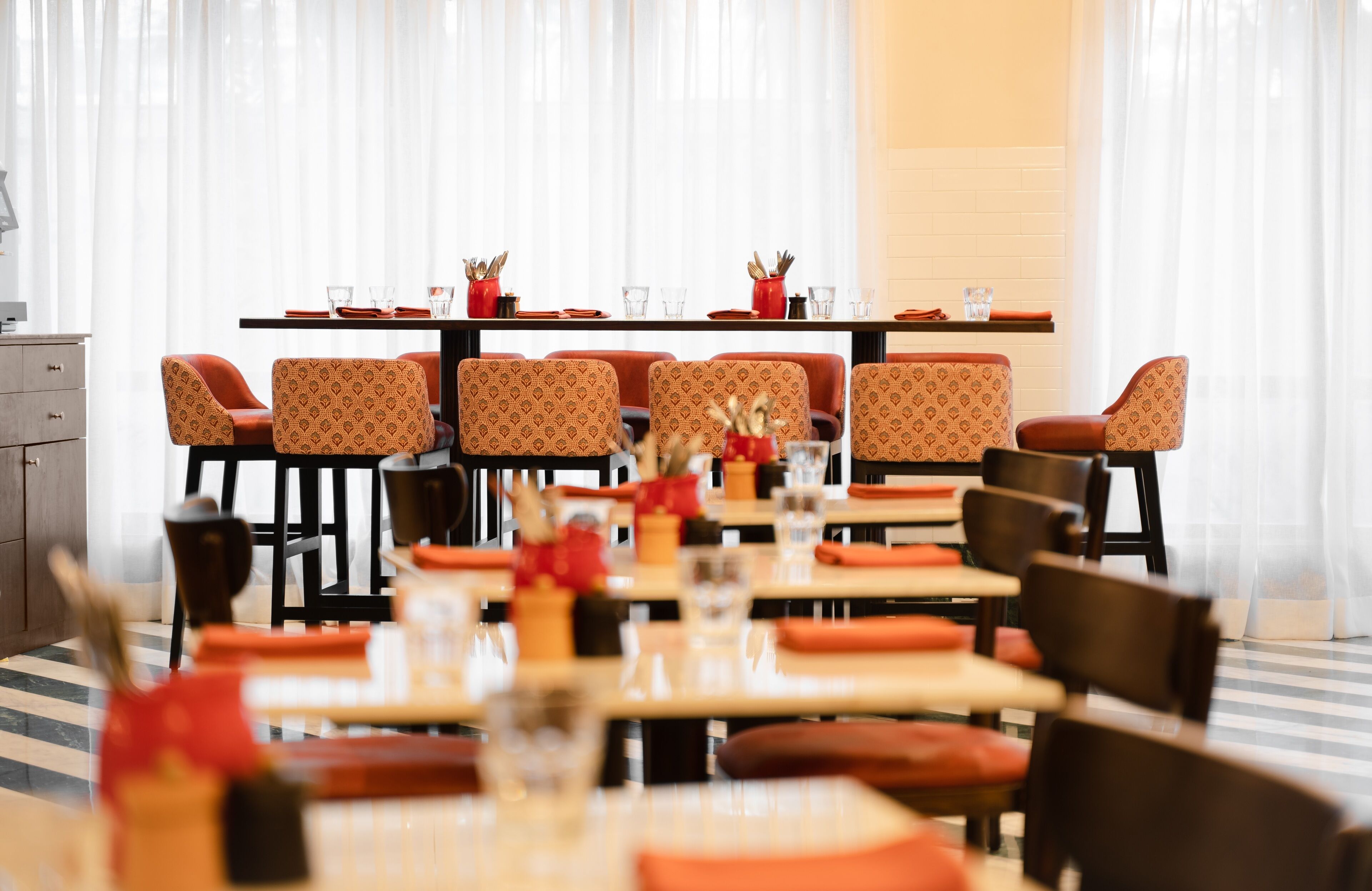 A restaurant with a long table set for dining, multiple chairs, and a clean, modern interior.