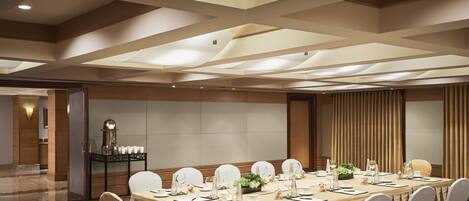 A conference room with a long table set for meetings, equipped with chairs, tables, and various amenities.