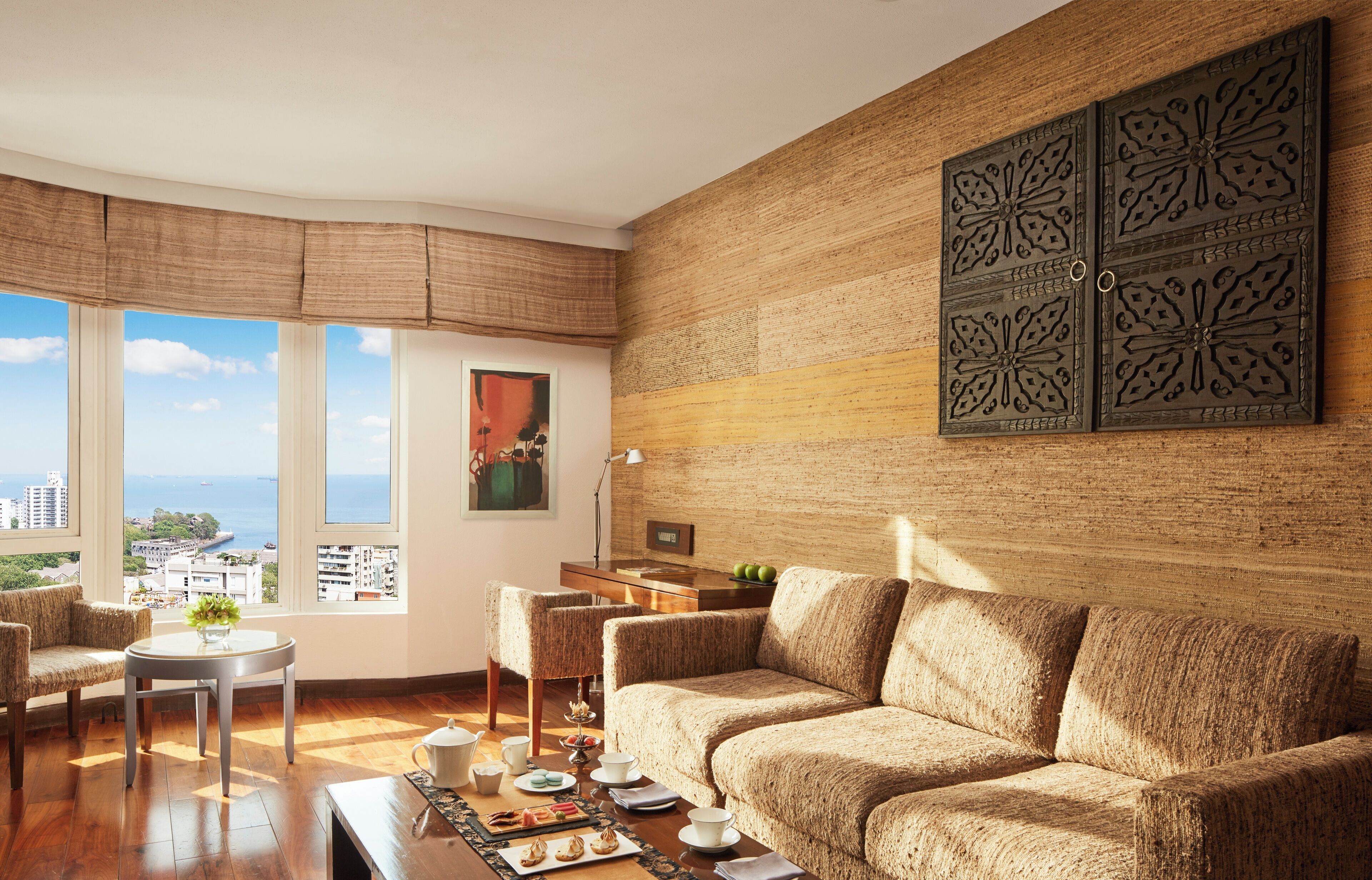 Una sala de estar con un ventanal grande, un sofá, una mesita y paneles decorativos en la pared.